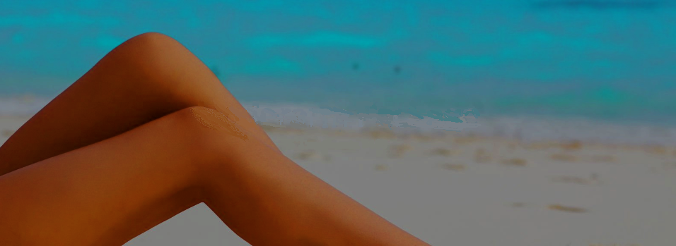 Tanned knees slightly raised of model lying on beach with littoral in background.